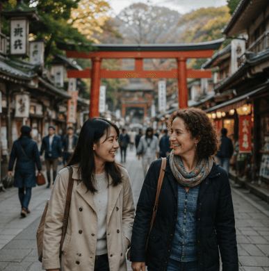 赤い鳥居を背景に、伝統的な日本の街並みを笑顔で歩く二人の女性。
